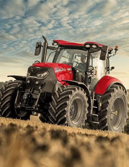 ractor agrícola Case IH Magnum 340 con cabina cerrada y diseño en rojo y negro, operando en un campo de cultivo bajo un cielo parcialmente nublado. Equipada con llantas anchas para mejor tracción en terrenos difíciles.